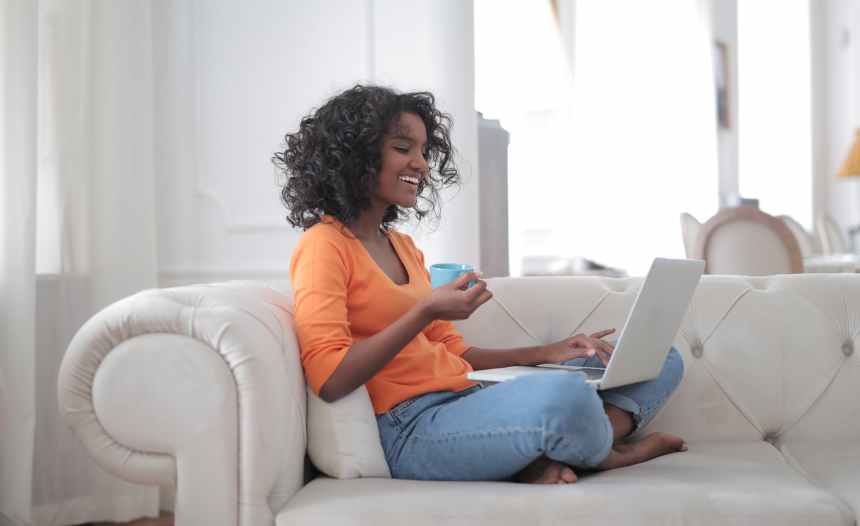 cheerful woman with cup of coffee surfing laptop